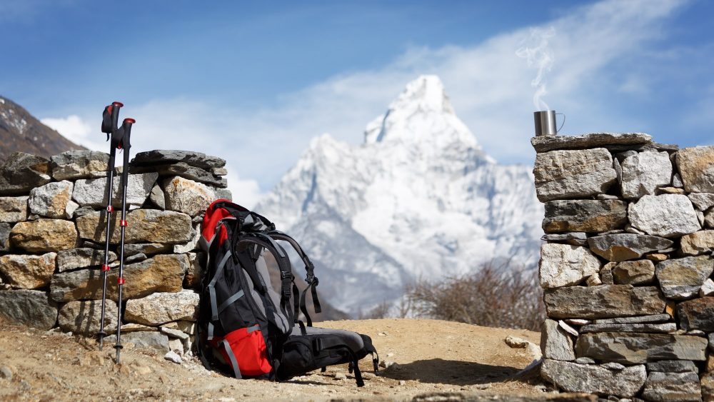 Trekking poles and backpack with mountain in the background