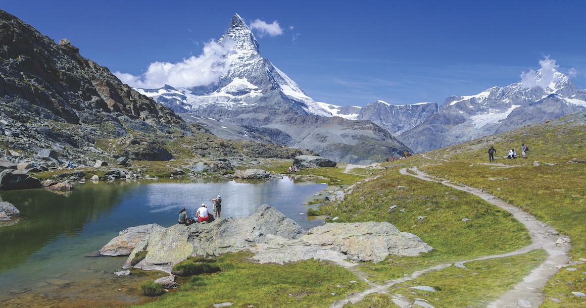 The Matterhorn in the distance with a lake a picnickers in the front.