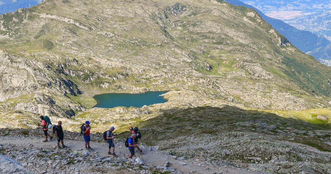 A group of hikers along the trail with a small lake in the distance.