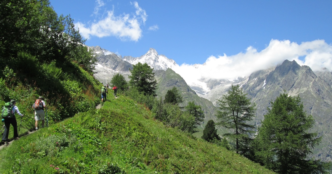 A few hikers make their way towards big peaks on a trail