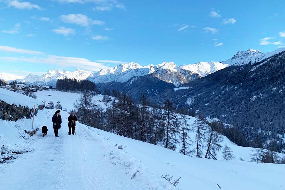 Two hikers on a snowy road with a mountain view