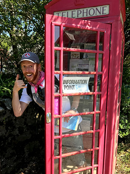 Rogan O'Herlihy exits a bright red phone booth in the Scottish Highlands.