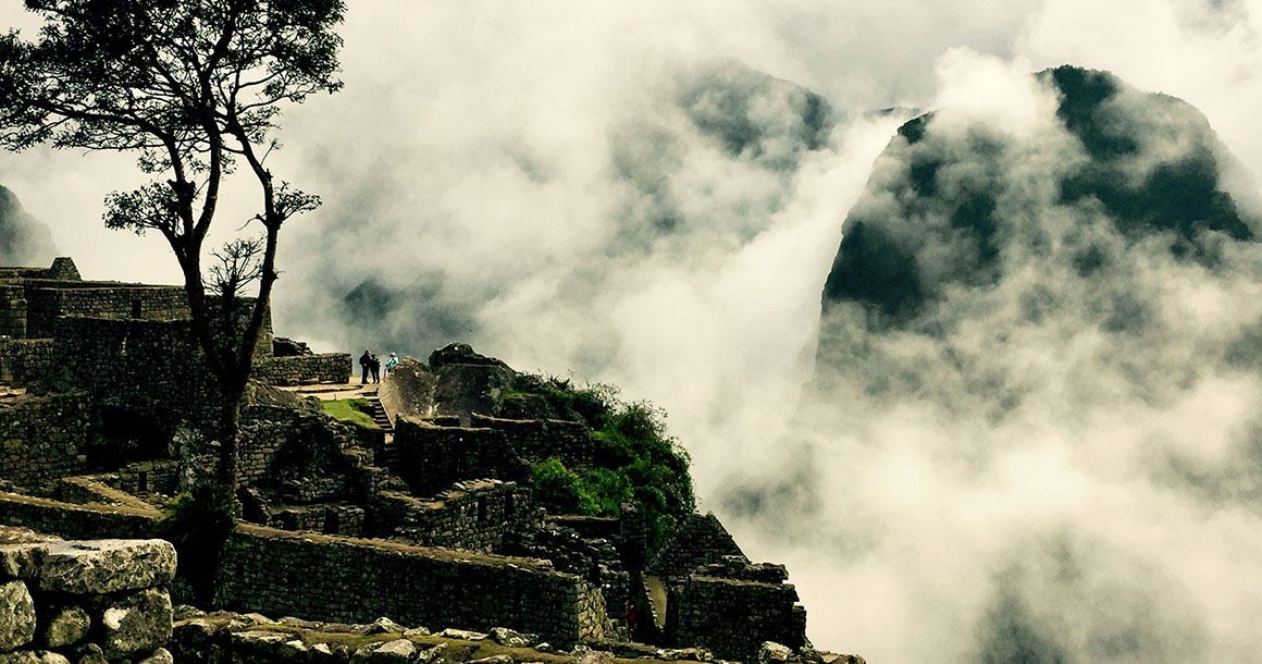 Machu Picchu with mountains shrouded in fog.