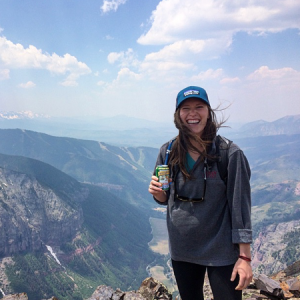 Woman standing on a mountain holding a beer