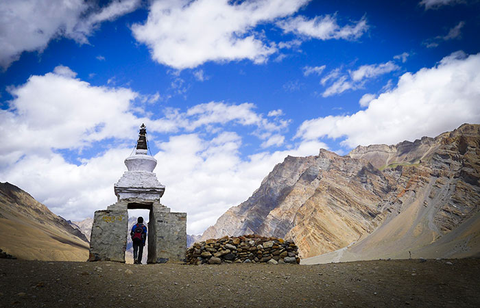 Man standing under a stone structure looking at mountains