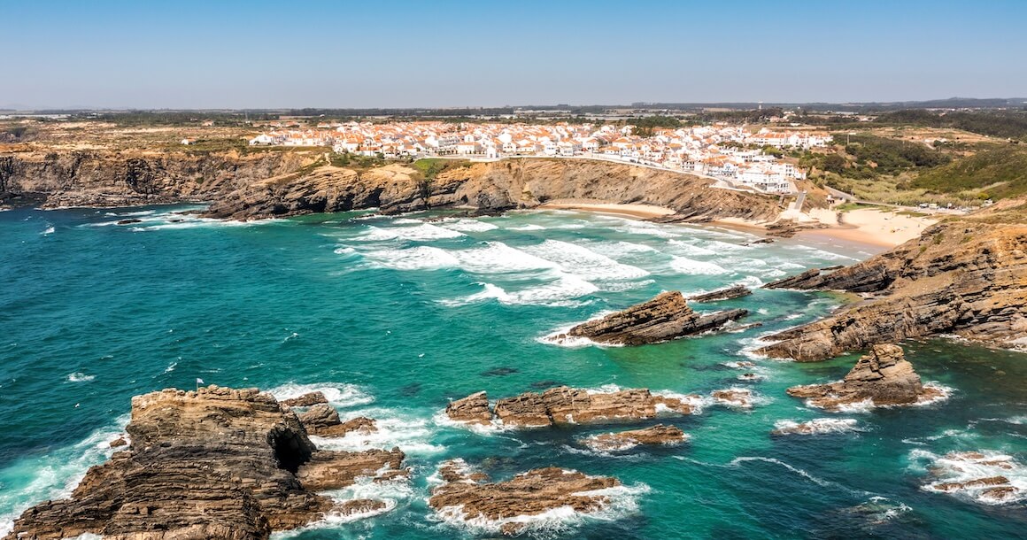 A town of white houses on a cliff with green ocean waters