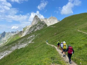 hikers on a trail with mountains in the background