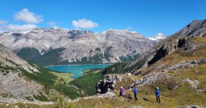 three people hiking to an alpine lake