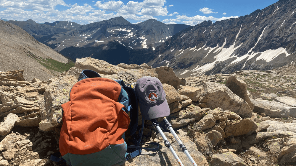 Backpack, trekking poles, and hat on the trail