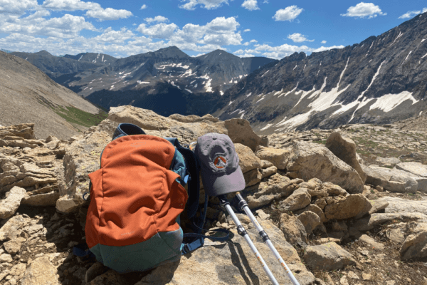 Backpack, trekking poles, and hat on the trail